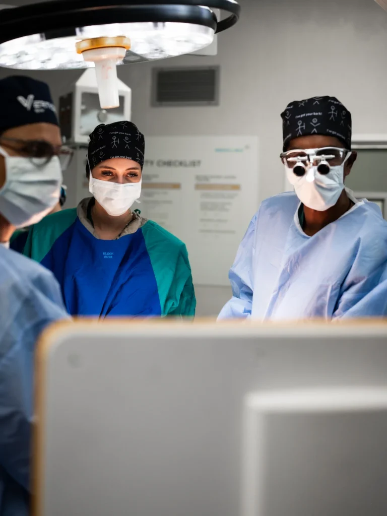 Operating theatre team performing specialist spine surgery in a modern surgical environment with advanced equipment.