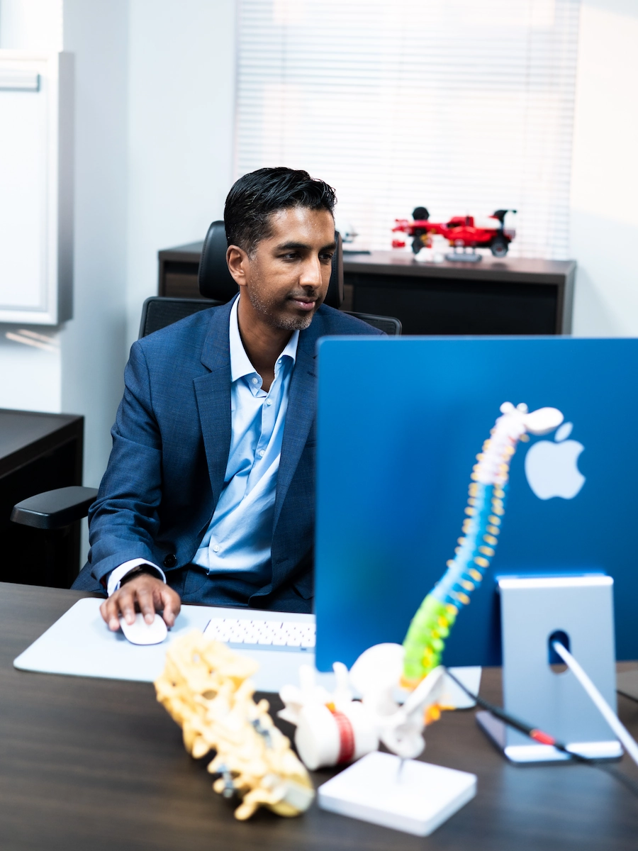 Dr Jaytesh Pillay reviewing spinal imaging and treatment planning for revision spine surgery consultation.