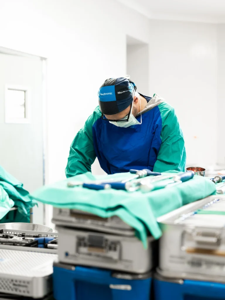 Specialist theatre professional preparing surgical equipment before advanced spine surgery with Dr Jaytesh Pillay.