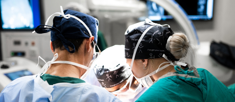 Specialist surgical team performing advanced spine surgery supported by ultrasonic bone scalpel technology